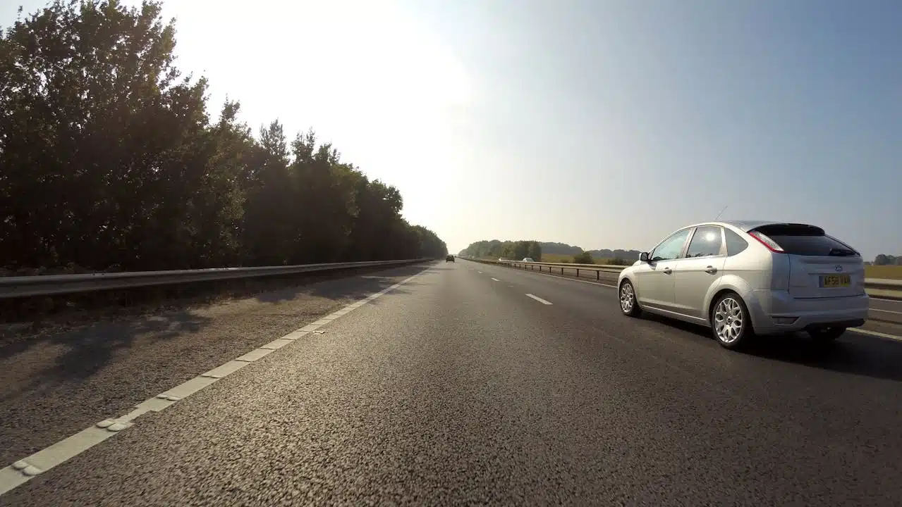 A car cruising on a scenic road under a clear sky.