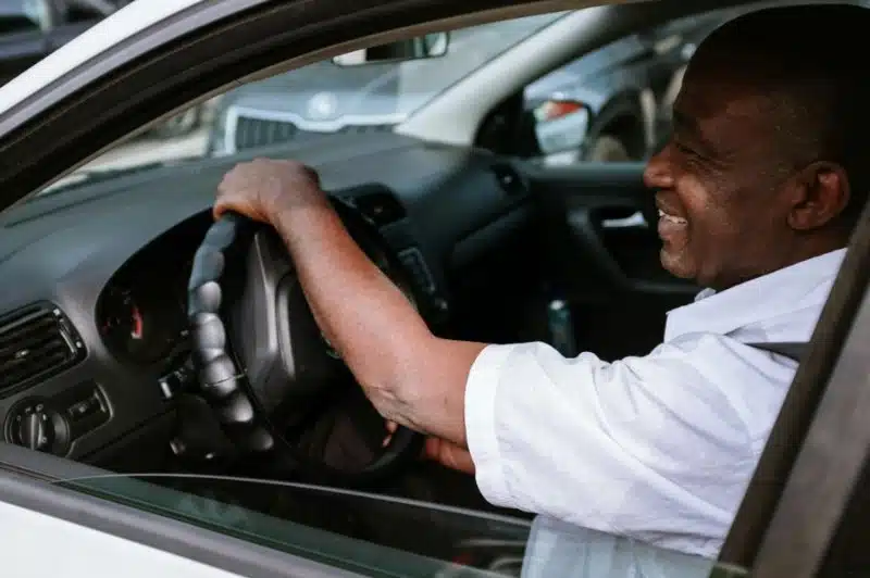 A man driving and smiling in his car, relaxed and confident.