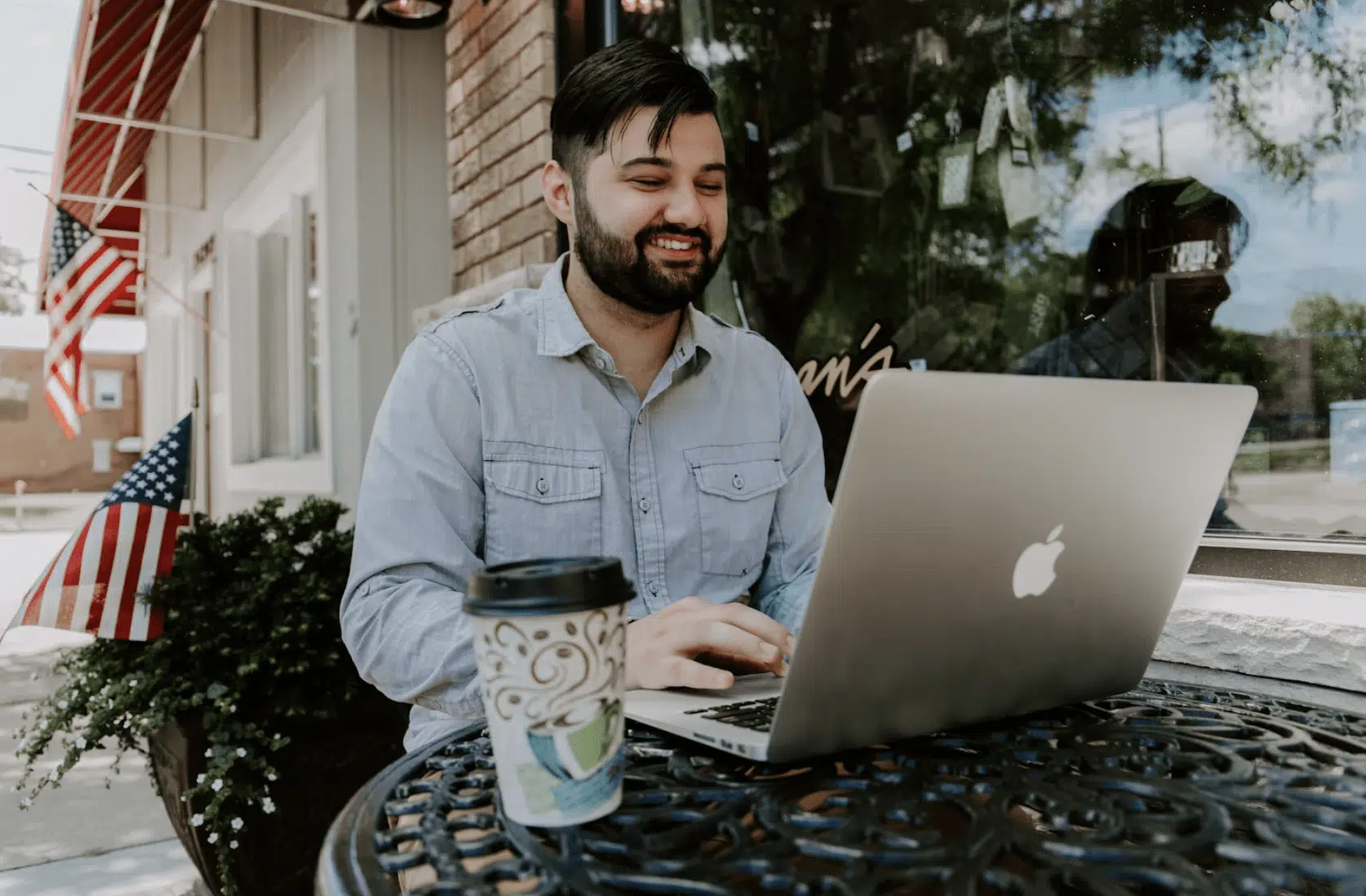 A man seated in a cafe, using his laptop to apply for an online title loan. 