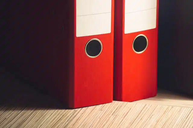 Two red paper binders standing side by side. 