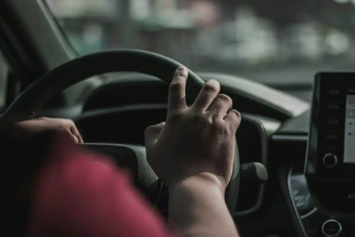 A person driving a car, with one hand on the steering wheel, symbolizing the importance of vehicle ownership for title pawns in Georgia.